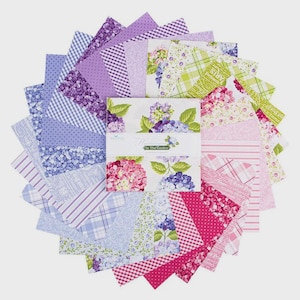 May include: A collection of fabric squares in a circular arrangement. The fabrics feature floral, gingham, and striped patterns in shades of pink, purple, and green. The center displays a label with the text "In The Garden".