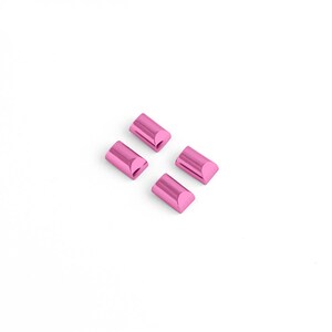 May include: Four small, pink, metallic cylinders arranged diagonally on a white background. Each cylinder has a rounded top and bottom with a flat, rectangular face. The objects appear to be components or parts.