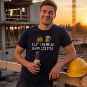 Peut inclure: Un t-shirt bleu marine à manches courtes arborant un motif de casque de chantier jaune et d'une chope de bière, avec le texte "ERST DER HELM, DANN DAS BIER" imprimé en lettres blanches sur la poitrine du vêtement.