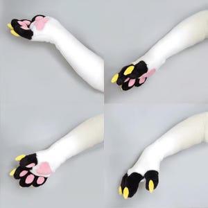 Pu&ograve; includere: Quattro viste di un braccio di peluche bianco con una zampa. La zampa presenta cuscinetti neri, cuscinetti rosa e artigli gialli. Il braccio &egrave; bianco e lo sfondo &egrave; grigio chiaro.