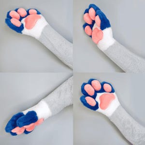 Pu&ograve; includere: Quattro immagini di una zampa di peluche con un braccio grigio, un polso bianco, cuscinetti blu e cuscinetti rosa. La zampa &egrave; in diverse posizioni, mostrando la parte superiore e inferiore della zampa.