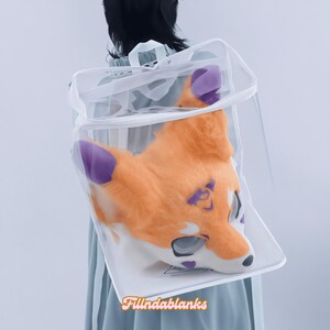 May include: A white mesh storage bag with a drawstring closure, containing a furry orange and purple fox head mask.