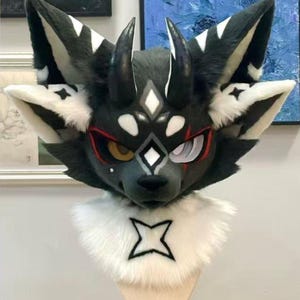 May include: A detailed furry head with a wolf-like design. The head is primarily dark gray with white accents on the ears and face. It features black horns, a white collar with a black star design, and expressive eyes with red and white details.
