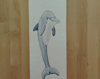 May include: A watercolour painting of a dolphin leaping out of the water. The dolphin is grey and white and has a long, slender body. The painting is on a white background.