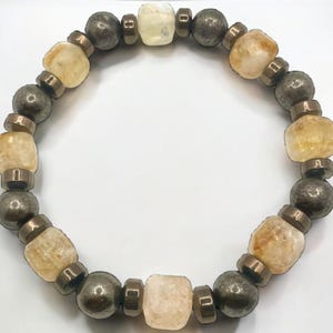 May include: A bracelet made of alternating light brown and dark brown beads. The light brown beads are faceted and the dark brown beads are round.