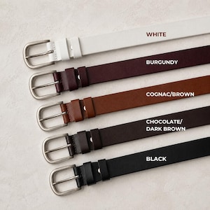 May include: Five belts with silver-toned metal buckles arranged vertically. The colors from top to bottom are white, burgundy, cognac brown, chocolate dark brown, and black. Each belt features a matching loop and a single prong metal buckle.