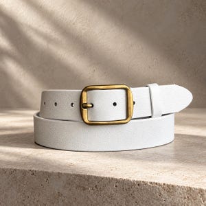 May include: A white belt with a textured surface and a rectangular antique brass buckle. The belt features a single matching white leather loop and a series of evenly spaced circular adjustment holes along the strap length.