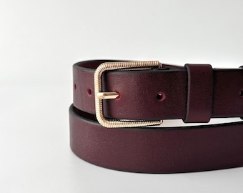 Cinturón de piel burdeos: hebilla dorada texturizada, elegante accesorio de piel color rojo vino para mujer.