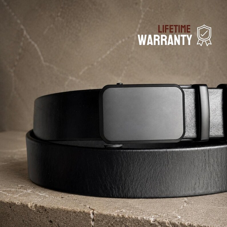 May include: A black leather belt featuring a smooth, rectangular matte black buckle and a matching black belt loop. The text "LIFETIME WARRANTY" is printed in the upper right corner next to a shield icon with a checkmark inside.