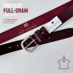 May include: A deep burgundy full-grain leather belt featuring a silver-toned metal buckle and a white tag with the text NO NAME store. The belt strap is embossed with the NO NAME logo. Text on the image reads PREMIUM FULL-GRAIN LEATHER.