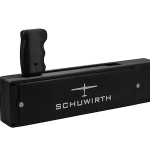 Peut inclure: Appareil rectangulaire noir avec une poignée et le mot SCHUWIRTH en blanc. Un graphique d'avion blanc est au-dessus du texte. La poignée est sur le côté supérieur gauche de l'appareil.