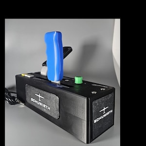 Op de afbeelding: Een zwarte doos met een blauwe gasklep en een groene knop. De doos heeft een wit logo met de tekst "SCHUWIRTH" en een klein vliegtuigsymbool.