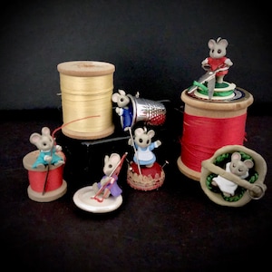 May include: A set of seven miniature mouse figurines, each depicting a different sewing-themed activity. The mice are sitting on spools of thread, a thimble, a pincushion, and a spool of thread with a needle and thread. The mice are wearing colorful clothing and have realistic details.