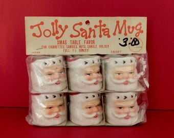 May include: A package of six white ceramic Santa mugs with red trim. The mugs are labeled "Jolly Santa Mug" and "Xmas Table Favor" with a price of "3.00".
