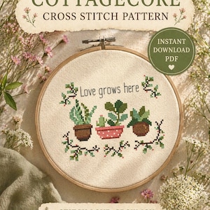 May include: A cross-stitch design featuring the phrase "Love grows here" and images of potted plants, set within a wooden embroidery hoop. The image also displays the text "Cottagecore Cross Stitch Pattern" and "Stitch Love. Grow Joy."