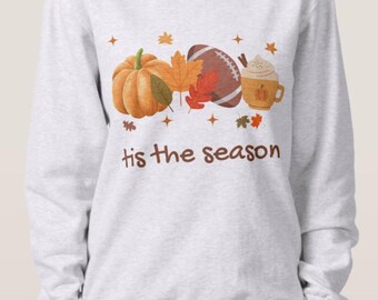 May include: A gray sweatshirt with a white graphic design featuring a pumpkin, football, leaves, and a cup of coffee. The text "'tis the season" is printed below the graphic.