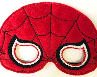 Op de afbeelding: Een rood viltmasker met een zwart geborduurd spinnenwebpatroon op het oppervlak. Het masker heeft twee oogopeningen die zijn omlijnd met dikke zwarte en witte stiksels. Aan beide zijden van het masker is een dun zwart elastisch koord bevestigd.