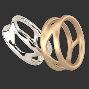 May include: Two rings, one silver and one gold, with an open, geometric design. The rings are stacked on top of each other.