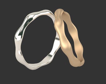 May include: Two wavy wedding bands, one silver and one gold, are intertwined.