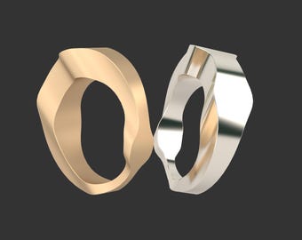 May include: Two rings, one gold and one silver, are intertwined and appear to be made of a smooth, polished metal. The rings are both oval shaped and have a unique, organic design.