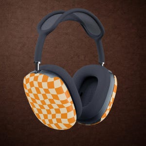 May include: Over-ear headphones featuring a dark gray headband and ear cushions with a distinctive orange and cream wavy checkerboard pattern on the outer ear cups. The design includes a mesh canopy on the headband and metallic adjustment arms.