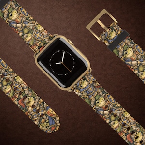 May include: Gold Apple Watch with a black screen and a patterned watch strap. The strap features a repeating design of cartoon frogs in medieval armour, with blue, green, and red accents. The buckle is gold.