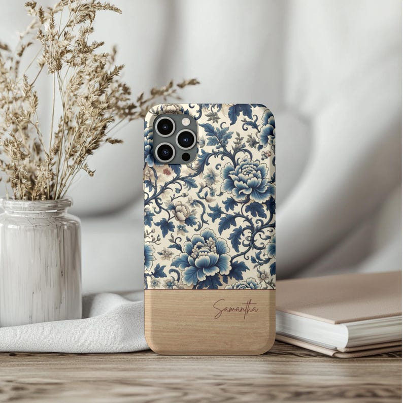 Pode incluir: Capa de telem&oacute;vel com um design floral em tons de azul e creme. A parte superior apresenta um padr&atilde;o detalhado de flores e folhas, enquanto a parte inferior tem um acabamento em madeira com o nome "Samantha" em escrita cursiva.