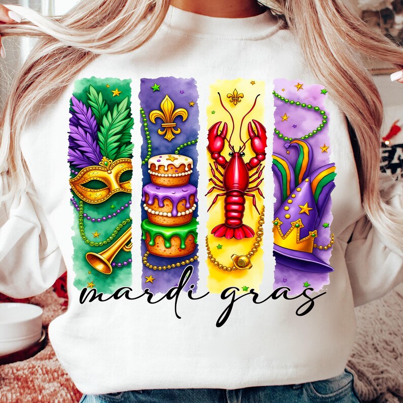 May include: White sweatshirt with a colorful graphic design featuring Mardi Gras symbols like a mask, a king cake, a crawfish, and a jester's hat. The text "Mardi Gras" is printed below the graphic.