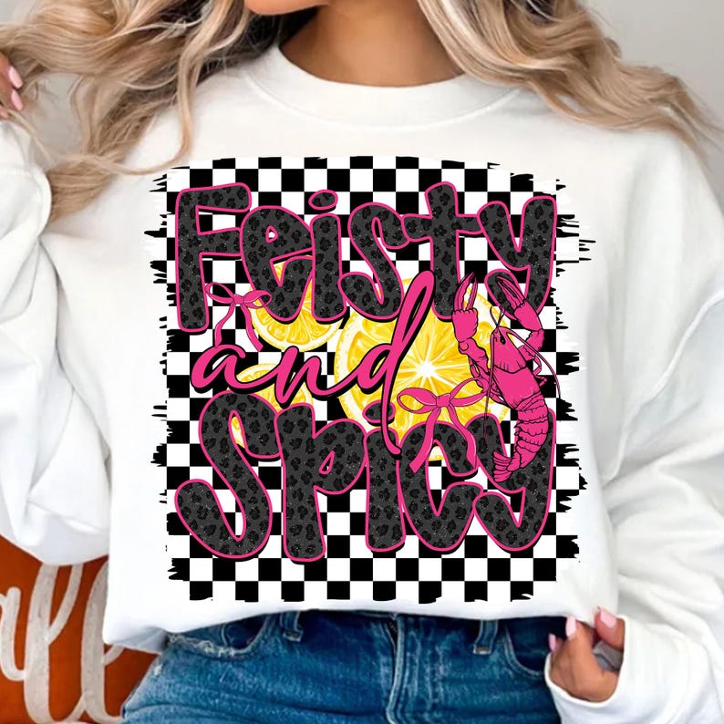 May include: White sweatshirt with a black and white checkered background. The text "Feisty and Spicy" is written in pink and black letters with a lemon and a pink crawfish graphic.