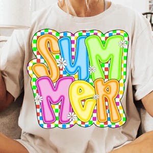 May include: A white t-shirt with a colorful graphic of the word "SUMMER" in a retro style. The letters are outlined in black and have a checkered background.