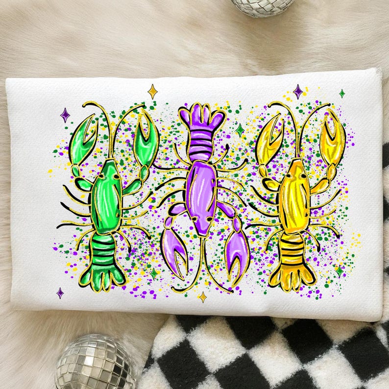 May include: White rectangular pillow featuring three colorful crawfish illustrations. The crawfish are in green, purple, and yellow with gold outlines, surrounded by green, purple, and yellow paint splatters and star accents. The pillow is on a white surface.