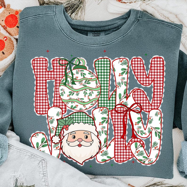 May include: A blue-green sweatshirt with the words "HOLLY JOLLY" in a festive design. The letters are filled with patterns of red gingham, green plaid, and white floral prints. A Santa Claus graphic is featured below the letter "H".