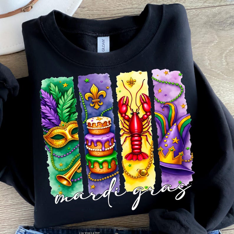 May include: Black sweatshirt with a colorful Mardi Gras design. The design features a mask, cake, crawfish, and a jester's hat. The text "Mardi Gras" is written in white letters at the bottom.