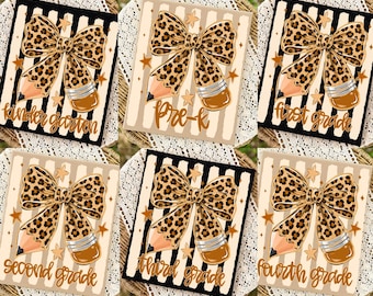 May include: A set of six square signs featuring a leopard print bow combined with a pencil design, accented by small stars. Each sign displays a different grade level in cursive text: kindergarten, pre-k, first grade, second grade, third grade, and fourth grade.