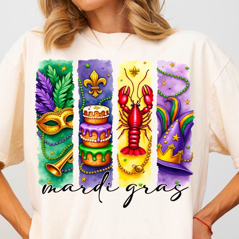 May include: A white t-shirt with a colorful graphic design featuring Mardi Gras symbols. The design includes a purple, green, and gold mask, a king cake, a red crawfish, and a purple, green, and gold jester hat. The text "Mardi Gras" is printed below the design.