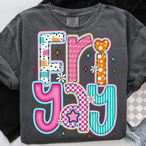 May include: A gray t-shirt with a colorful graphic design that says "Friyay" in a playful, patchwork style. The design features a variety of patterns, including polka dots, stripes, and checkered.