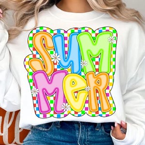 May include: White sweatshirt with a colorful "Summer" graphic. The letters are outlined in neon colors and have a checkered background.