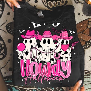 May include: Black sweatshirt with a Halloween-themed graphic. The design features three ghost figures wearing pink cowboy hats and bandanas, holding a lasso and a toy gun. The text "Howdy Halloween" is in pink.