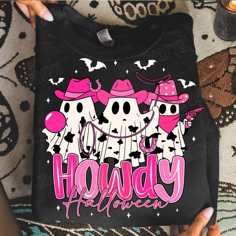 May include: Black sweatshirt with a Halloween-themed graphic. The design features three ghost figures wearing pink cowboy hats and bandanas, holding a lasso and a toy gun. The text "Howdy Halloween" is in pink.