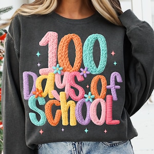 Puede incluir: Sudadera gris oscuro con el texto "100 Days of School" en letras coloridas y texturizadas. Las letras son rosas, naranjas, azules, amarillas y moradas, con pequeños detalles florales.