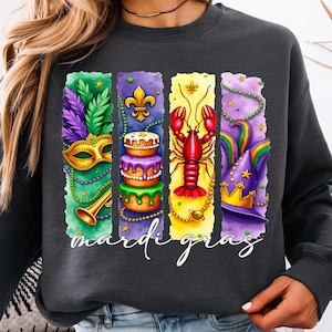 May include: A dark gray sweatshirt with a colorful Mardi Gras design. The design features a mask, a cake, a crawfish, and a hat with stars. The text "Mardi Gras" is printed below the design.