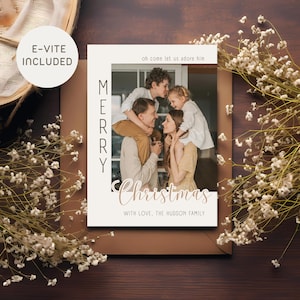 May include: A Christmas card featuring a family photo within a cream-coloured frame. The card displays "Merry Christmas" in a script font, with the text "Oh come let us adore him" above the photo. The words "E-vite Included" are in a circle in the upper left corner.