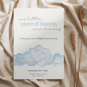 May include: Baby shower invitation with the text "our little piece of heaven is on his way." The invitation features a watercolor cloud design in shades of blue and includes event details: date, time, and location.