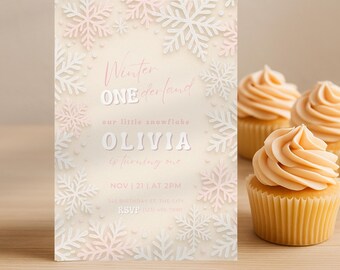 Peut inclure: Une invitation d'anniversaire sur le thème de l'hiver avec des flocons de neige et le texte "Winter ONE derland". L'invitation est beige clair avec des détails roses et blancs. Trois cupcakes avec glaçage orange en arrière-plan.