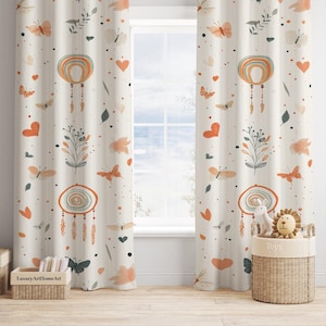 May include: Two cream-colored curtains with a repeating pattern of orange, red, and green dreamcatchers, butterflies, hearts, and leaves. The curtains are hung in a window with a white window frame. A wicker basket with the word "Toys" on it is in the lower right corner of the image.