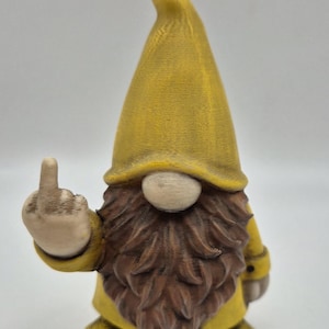 May include: A novelty garden gnome figure, dressed in yellow with a pointed hat and a brown beard. The gnome is raising its middle finger, adding a humorous element. This figurine is a unique decorative item for the garden.