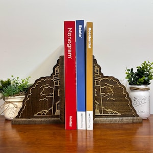 Pode incluir: Suportes de livros de madeira com um design de farol, com três livros intitulados "Monogram", "Estate" e "Residential".