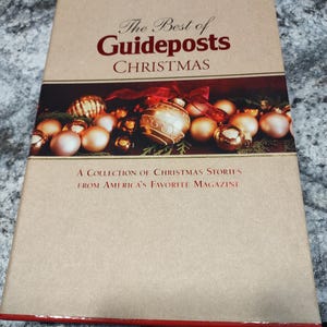 Peut inclure: Un livre brun avec une reliure rouge intitulé "The Best of Guideposts CHRISTMAS" avec un recueil d'histoires de Noël du magazine préféré d'Amérique. La couverture présente un ruban rouge et des boules de Noël dorées.