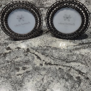 May include: Two black metal picture frames with a woven design. Each frame has a white background with the text "valerie bertinelli" printed in black.