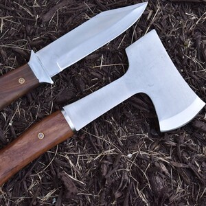 May include: A set of two tools with wooden handles. The first tool is a knife with a silver blade and a brown wooden handle. The second tool is a small axe with a silver blade and a brown wooden handle. Both tools have brass accents on the handles.